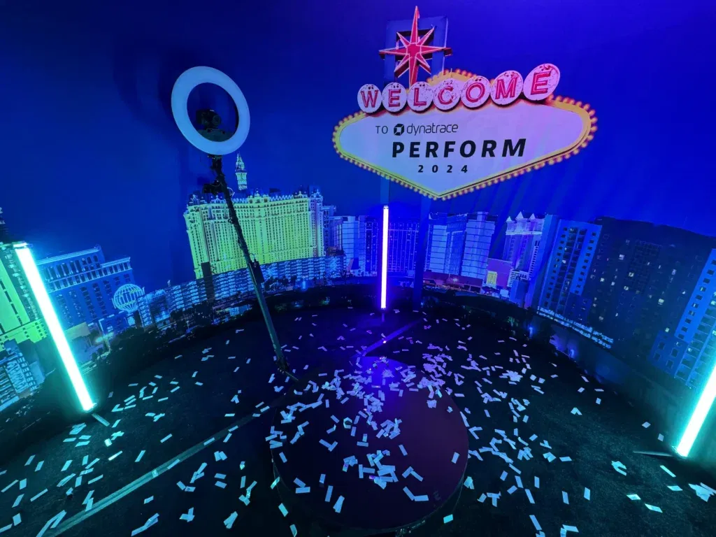A 360 camera setup with neon lighting and a Las Vegas-themed backdrop shown as a photo booth idea for corporate events