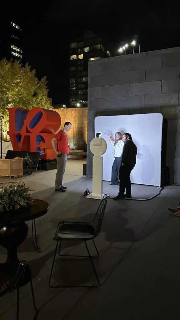 An outdoor AI-powered photo booth in use during a nighttime corporate event. 